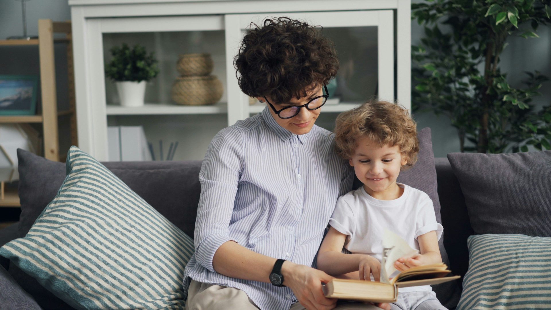 a woman sitting on a couch reading a book to a child